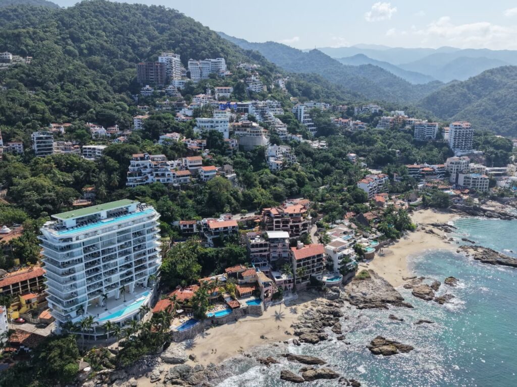 Aerial view of Conchas Chinas in Puerto Vallarta with luxury beachfront villas and lush green hills
