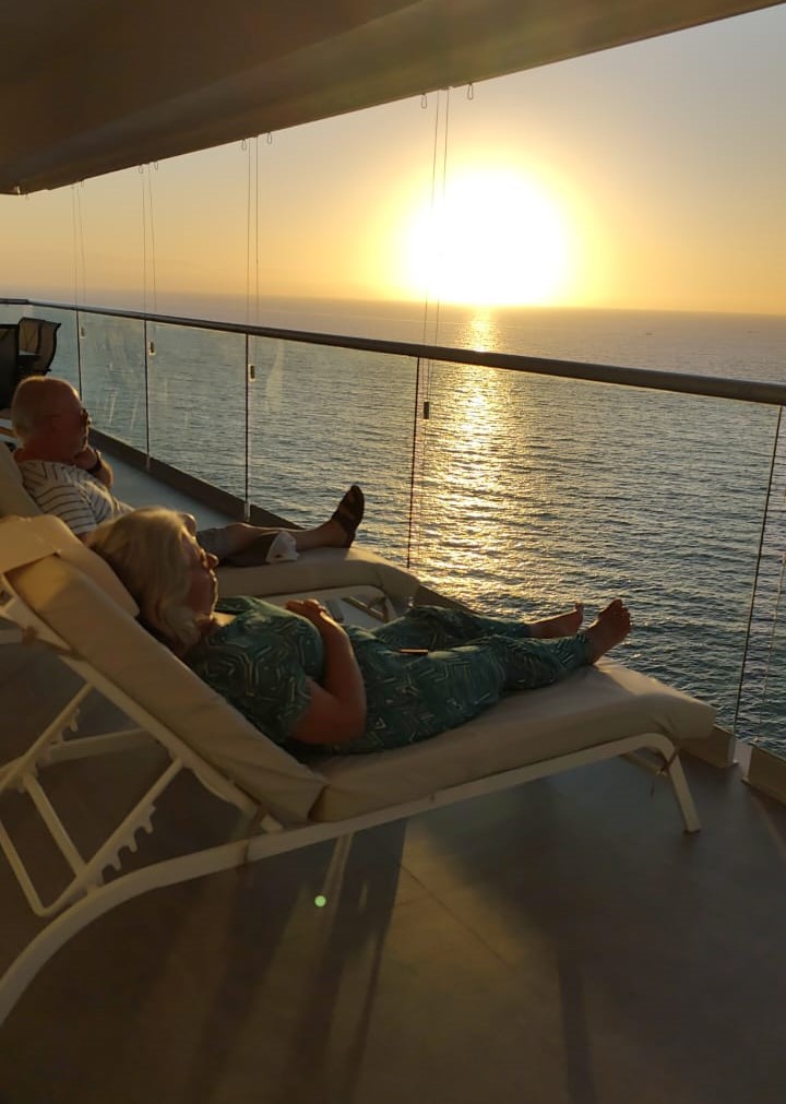 Older American couple relaxing on a balcony overlooking the ocean at sunset in Mexico