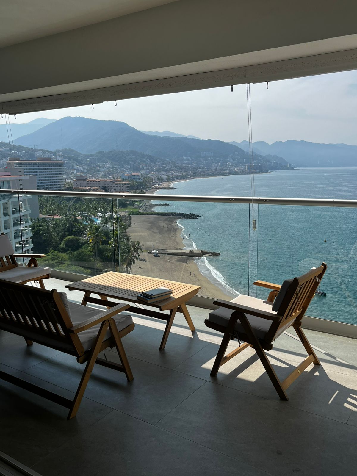 Ocean view from a luxury penthouse balcony with wooden outdoor seating in Puerto Vallarta