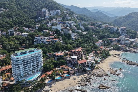 Aerial view of Conchas Chinas in Puerto Vallarta with luxury beachfront villas and lush green hills