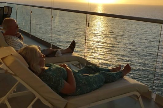 Older American couple relaxing on a balcony overlooking the ocean at sunset in Mexico